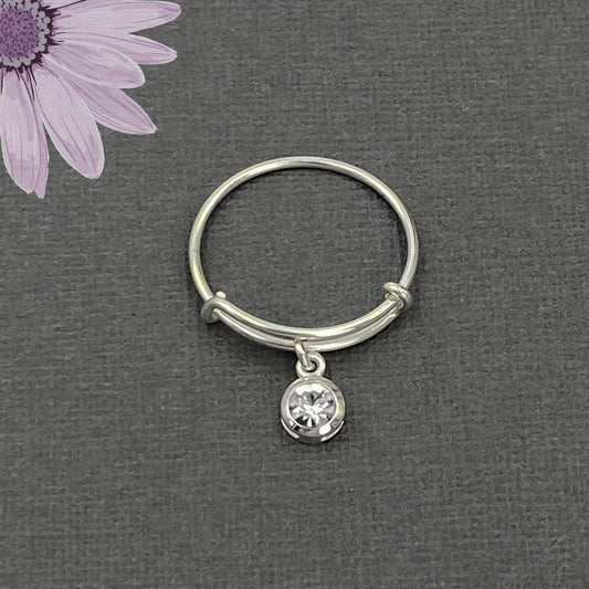 Close up shiny sterling silver band ring that is adjustable and has a sparkly crystal dangle loosely hanging from the silver band. Womens adjustable rings.