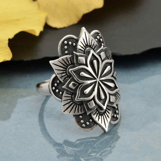 A stunning statement ring for women with a large intricate mandala shape in shiny sterling silver with darker patinas inlayed.  The mandala is floral shaped with petals. Zen rings for women. 